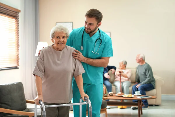 Care worker helping to elderly woman with walker in geriatric ho — 스톡 사진