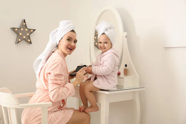 Young mother and little daughter doing makeup at dressing table — 스톡 사진