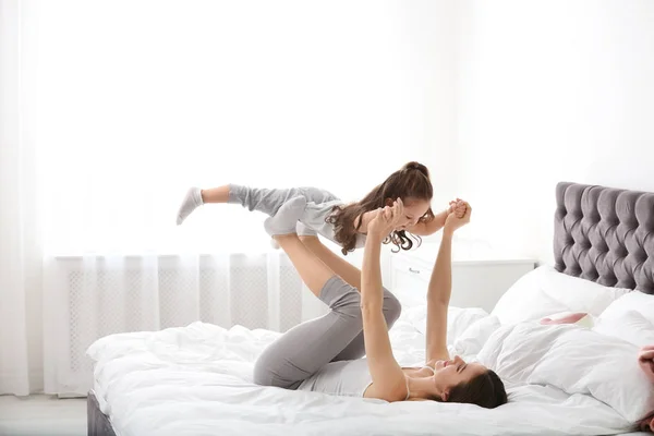 Happy mother with little daughter playing on bed — ストック写真