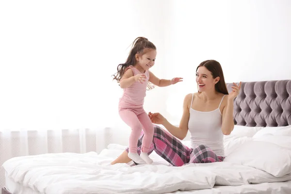 Madre feliz con hija pequeña jugando en la cama — Foto de Stock