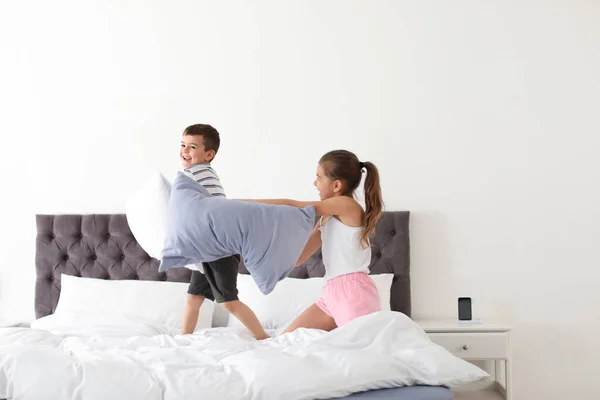 Niños felices teniendo pelea de almohadas en el dormitorio —  Fotos de Stock