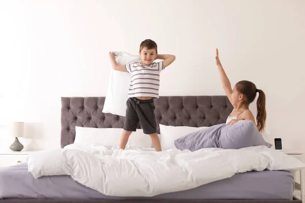 Niños felices teniendo pelea de almohadas en el dormitorio —  Fotos de Stock