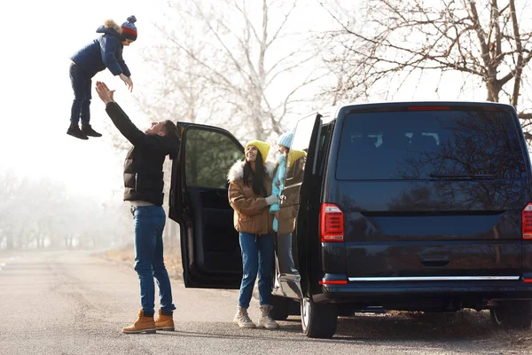 Щаслива сім'я з маленькими дітьми біля сучасної машини на дорозі — стокове фото