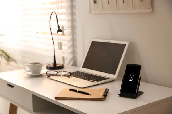 Elegante lugar de trabajo con portátil, teléfono móvil y cargador inalámbrico —  Fotos de Stock