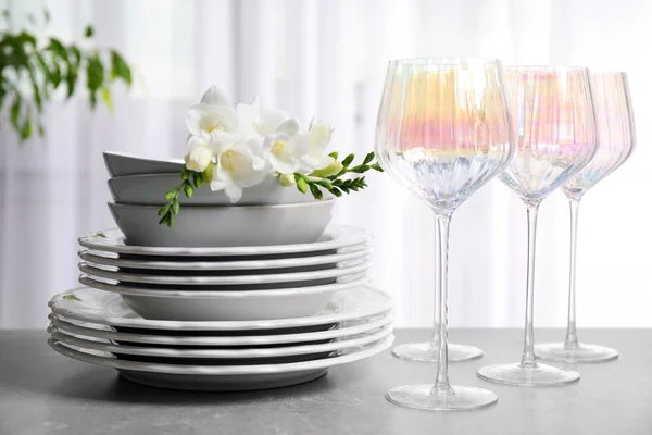 Uppsättning glasögon och tallrikar med blommor på ljusgrå bord — Stockfoto