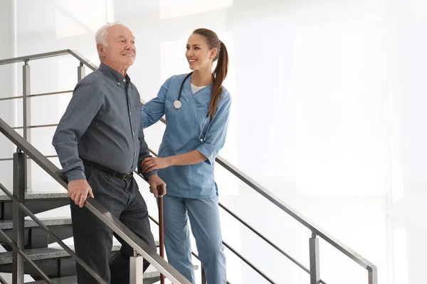 Medico che aiuta il paziente anziano nell'ospedale moderno — Foto Stock