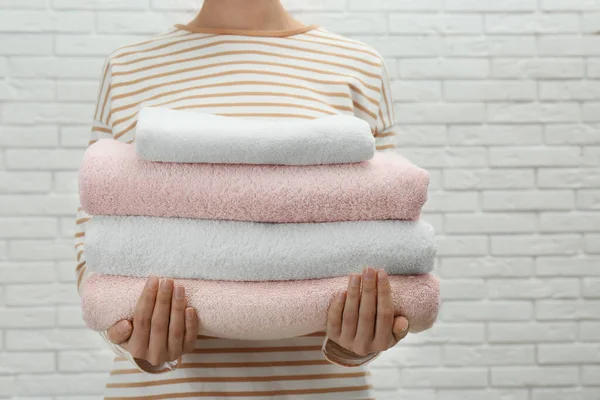 Vrouw met verse handdoeken tegen witte bakstenen muur, close-up — Stockfoto