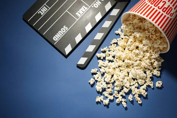 Deliciosas palomitas de maíz y claqueta sobre fondo azul, por encima de la competencia — Foto de Stock