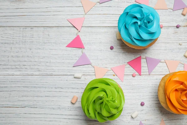 Cupcakes coloridos de aniversário na mesa de madeira branca, flat lay. Espada. — Fotografia de Stock