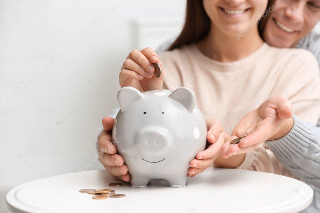 Couple with piggy bank at white table, closeup