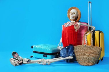 Human skeleton in summer clothes with suitcases on blue backgrou
