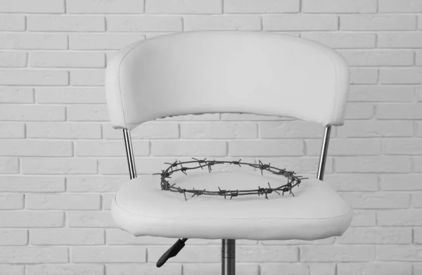 Chair with barbed wire near white brick wall. Hemorrhoids concept