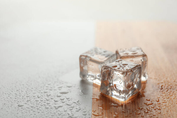 Crystal clear ice cubes with water drops on table. Space for text