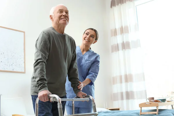 Care worker helping elderly man with walker in geriatric hospice — 스톡 사진