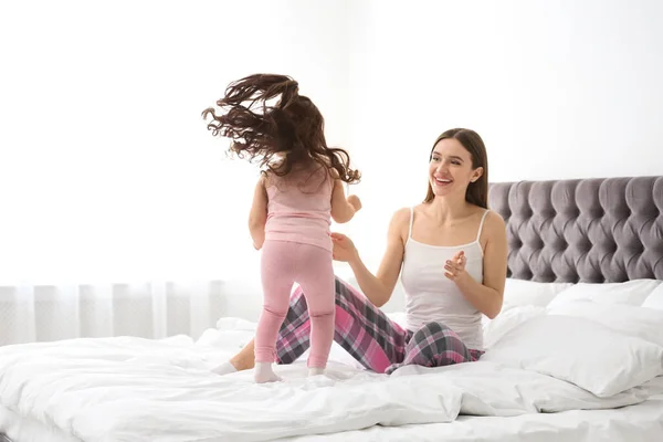 Madre feliz con hija pequeña jugando en la cama — Foto de Stock