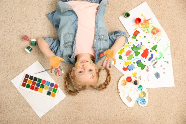 Cute little child with painted face and palms on floor, top view — Stock Photo, Image