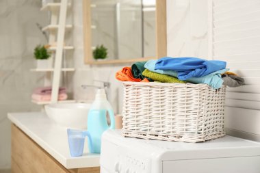 Çamaşır makinesinin üstünde çamaşır sepeti var.