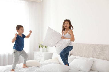Mutlu çocuklar yatak odasında yastık savaşı yapıyor.