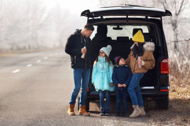 Happy family with little children near modern car on road