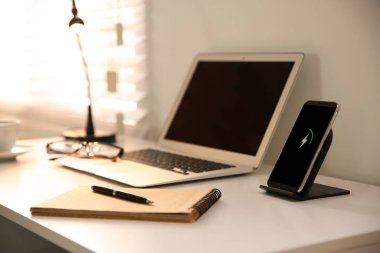 Dizüstü bilgisayarı, cep telefonu ve kablosuz şarjı olan şık bir iş yeri