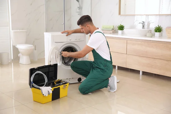 Professionell rörmokare reparera tvättmaskin i badrummet — Stockfoto