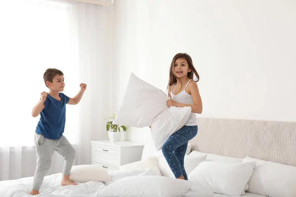 Счастливые дети дерутся на подушках в спальне — стоковое фото