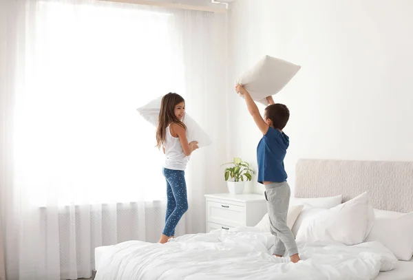 Счастливые дети дерутся на подушках в спальне — стоковое фото