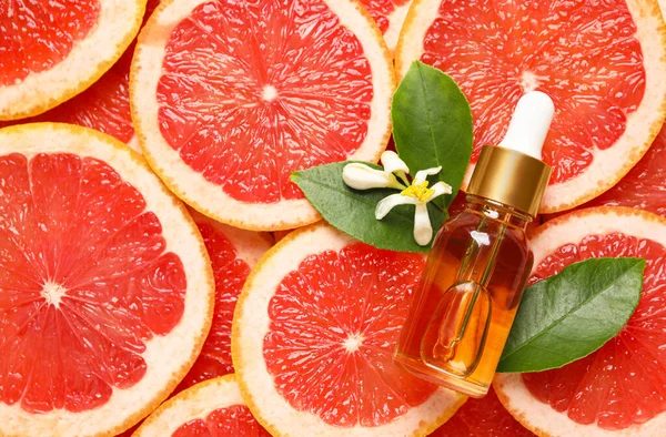 Bottle Citrus Essential Oil Flower Pile Grapefruit Slices Flat Lay — Stock Photo, Image