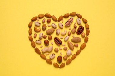 Sarı arka planda farklı fındıklardan yapılmış bir kalp.