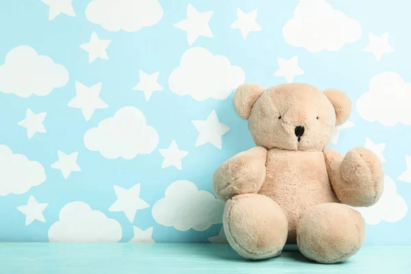 Teddy bear on wooden table near wall with painted blue sky, spac — Stock Photo, Image