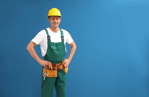 Handsome carpenter with tool belt on blue background. Space for — Stock Photo, Image