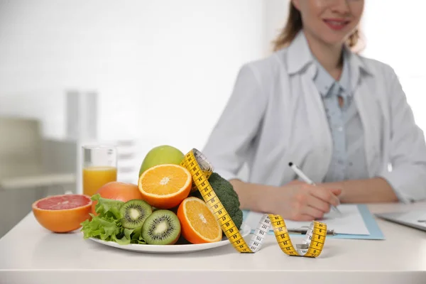 Nutritionniste au bureau avec fruits, légumes et ruban à mesurer — Photo