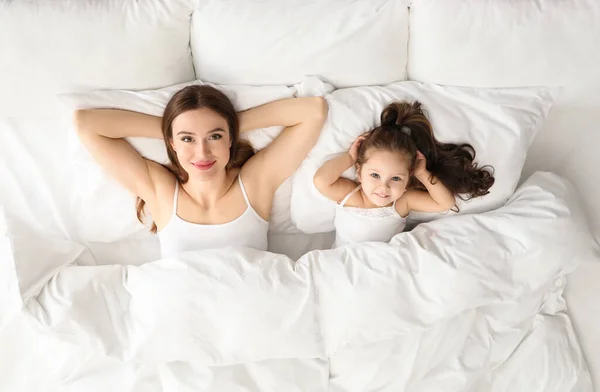 Mother and little daughter lying in bed, top view — 스톡 사진