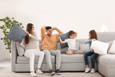 Mutlu aile oturma odasında yastık savaşı yapıyor.