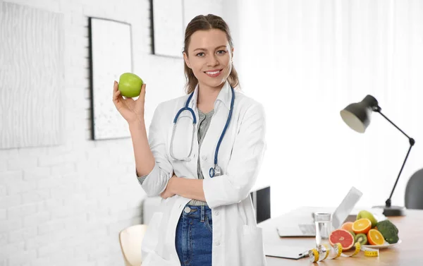 Διατροφολόγος με φρέσκο μήλο κοντά στο γραφείο στο γραφείο — Φωτογραφία Αρχείου