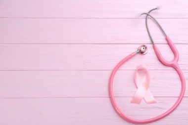Ahşap arka planda pembe kurdele ve steteskop. 