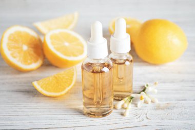 Beyaz ahşap masa üzerinde turunç, çiçek ve limon şişeleri.