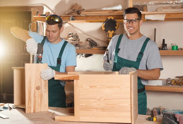 Profesjonalni stolarze montujący drewnianą szafkę w warsztacie — Zdjęcie stockowe
