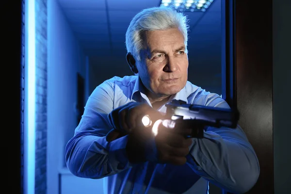Professional security guard with gun and flashlight checking dar — Stock Photo, Image