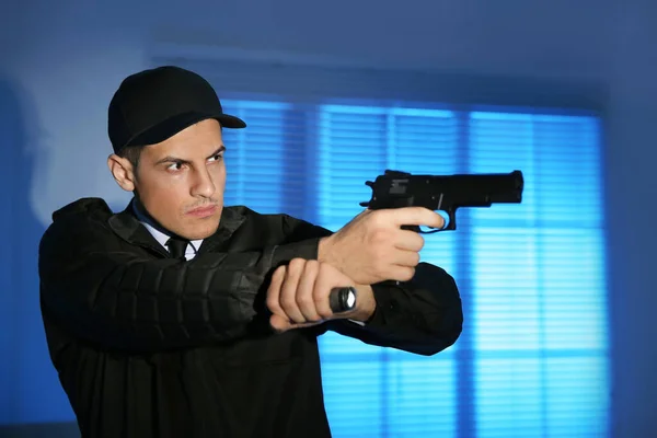 Professional security guard with flashlight and gun in dark room — Stock Photo, Image