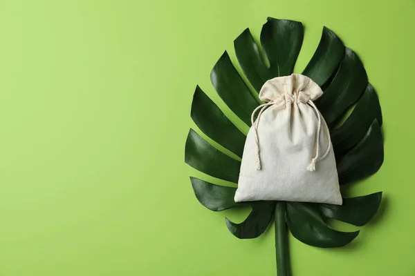 Cotton eco bag and monstera leaf, top view. Space for text