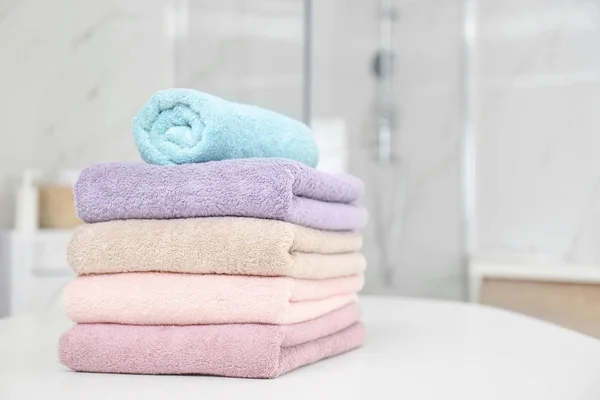 Stack of fresh towels on white table in bathroom. Space for text — Stock Photo, Image