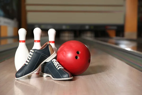 Shoes, pins and ball on bowling lane in club