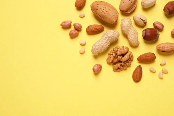 Diferentes deliciosas nueces sobre fondo amarillo, planas. Espacio f — Foto de Stock