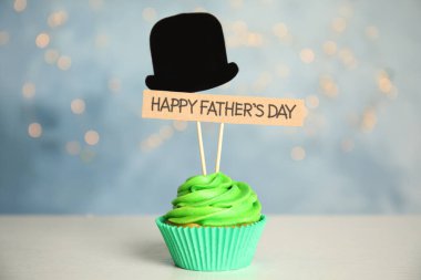 Kağıt şapkalı kek ve bulanık arka planda beyaz masada Mutlu Babalar Günü etiketi.