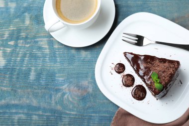 Açık mavi ahşap masa üzerinde naneli, nefis çikolatalı pasta. Metin için boşluk