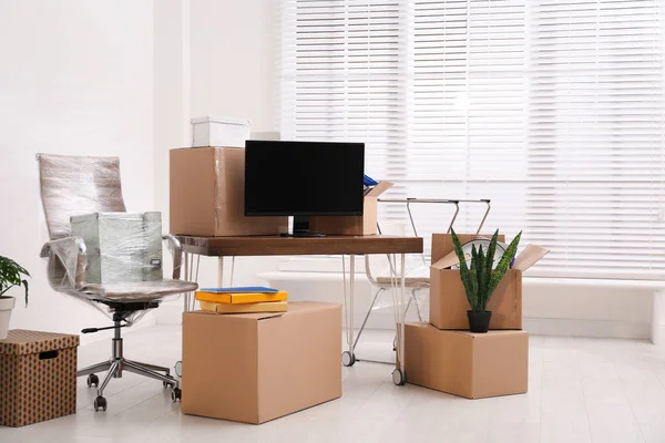 Cardboard boxes and packed belongings in office. Moving day