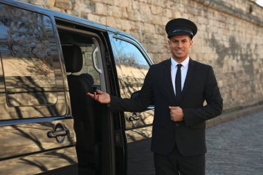 Lüks bir arabanın yanında profesyonel bir sürücü. Şoför servisi.