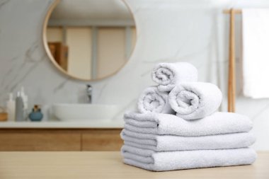 White towels on wooden table in bathroom. Space for text clipart