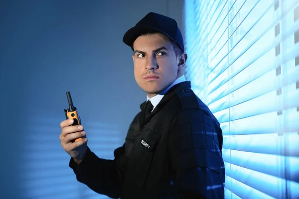 Професійний охоронець з портативним радіоприймачем біля вікна — стокове фото